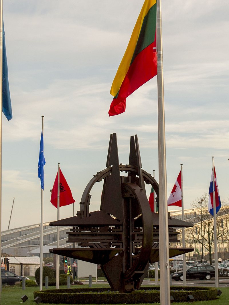 Member-nation flags encircling the NATO Star sculpture at NATO Headquarters in Brussels — opens the essay (PDF)